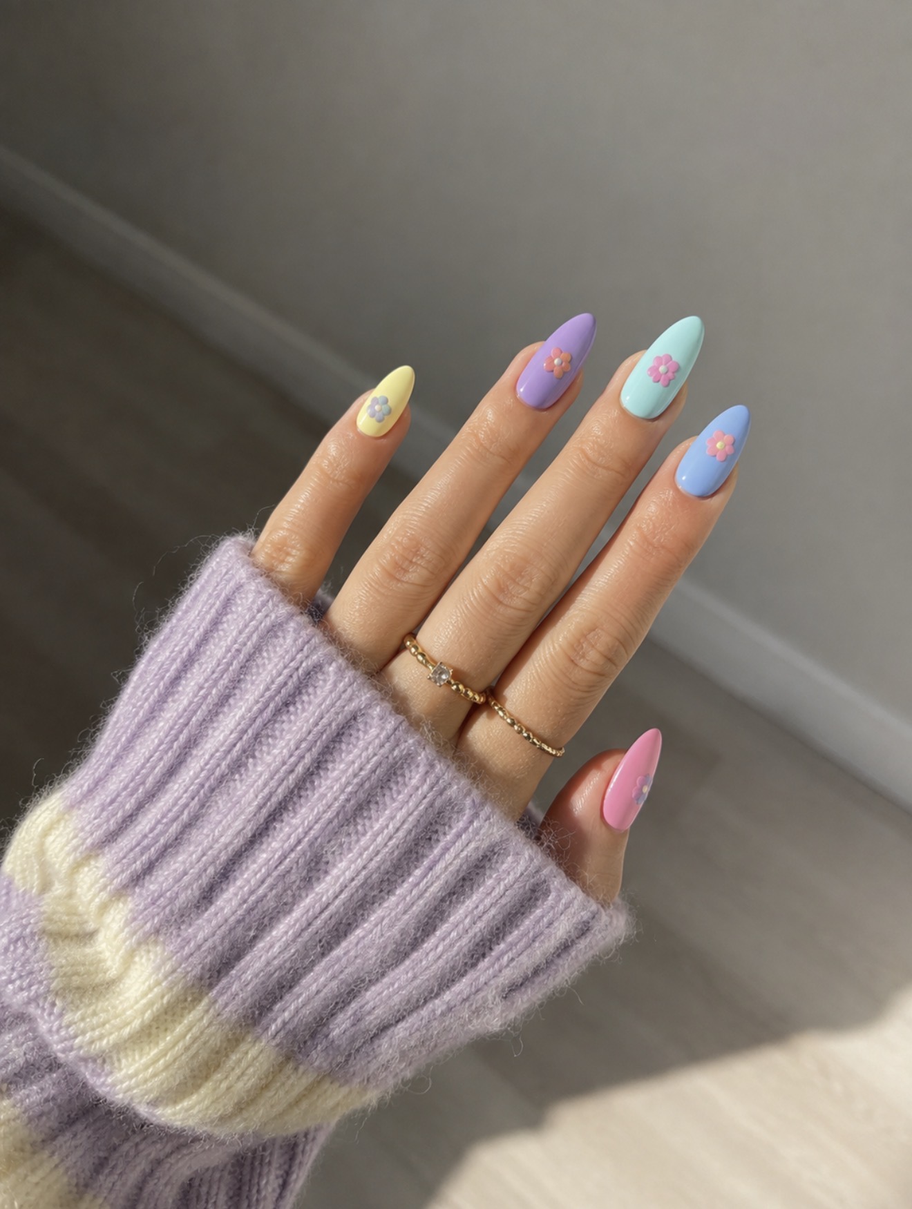 Pastel almond nails with daisy nail art in yellow, lilac, blue and pink