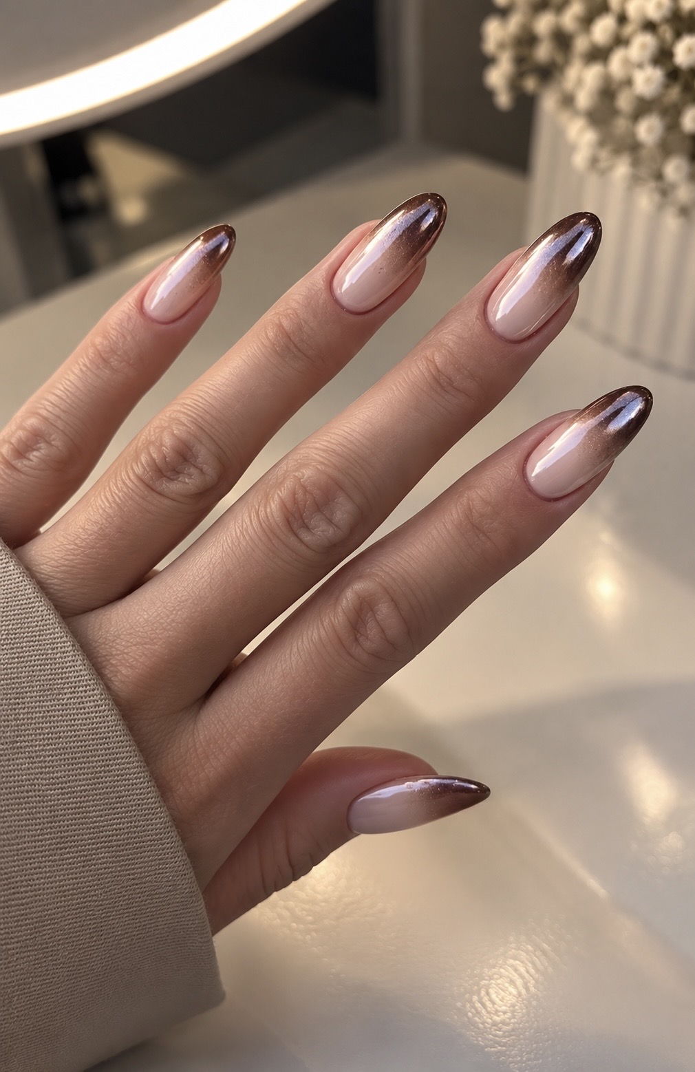 Chrome ombré nails fading from nude to bronze